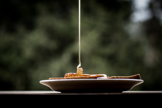 Honey being dripped onto a slice of brown toast
