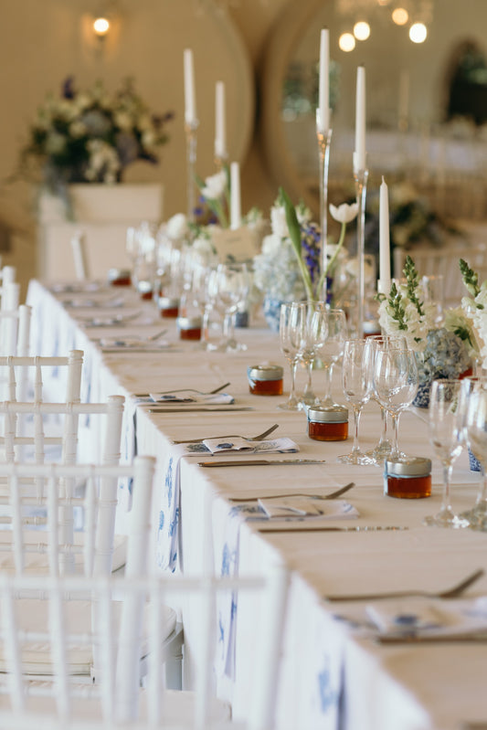 A white table with jars of honey on top as wedding gifts.